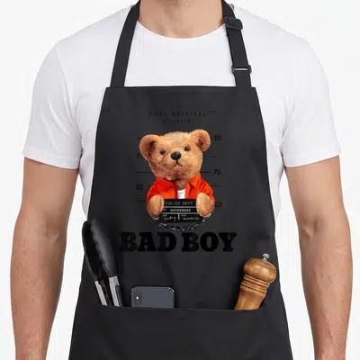 Tablier de cuisine noir avec illustration d'un ours en tenue de prisonnier et texte Bad Boy.