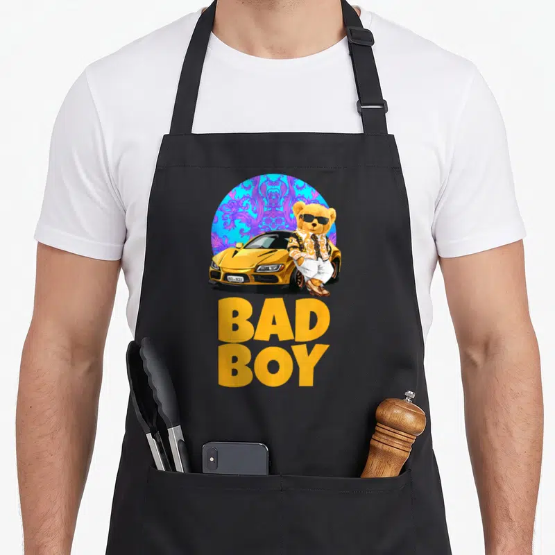 Tablier de cuisine noir avec un ourson bad boy en costume et voiture dorée sur fond bleu orné.