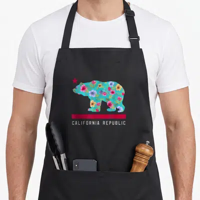 Tablier de cuisine noir avec silhouette d'ours remplie de fleurs colorées et l'inscription California Republic en blanc sous une bande rouge.