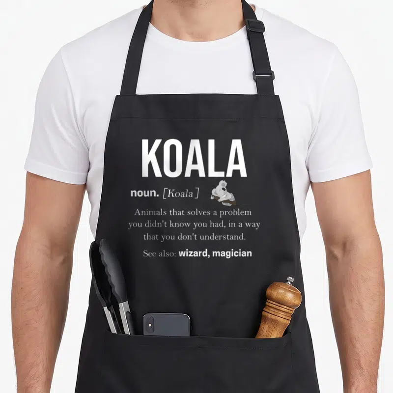 Tablier de cuisine noir avec illustration d'un koala grimpant à une branche et texte blanc imitant une entrée de dictionnaire.