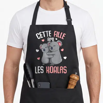 Tablier de cuisine noir avec deux koalas gris s'enlaçant entourés de petits coeurs roses et blancs et du texte cette fille aime les koalas.