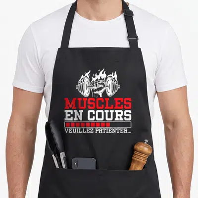 Tablier de cuisine noir avec poignet en feu soulevant une barre et texte muscles en cours veuillez patienter en rouge et blanc.
