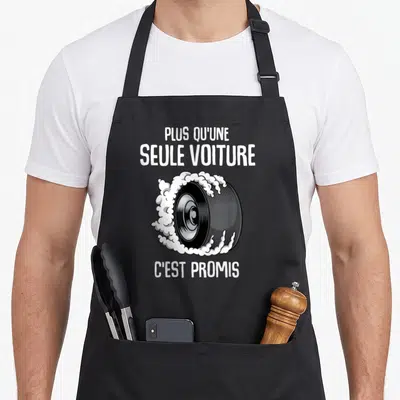 Tablier de cuisine noir avec illustration de pneu en train de dériver et texte blanc humoristique sur le côté.