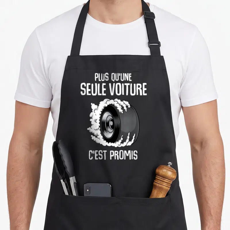 Tablier de cuisine noir avec illustration de pneu en train de dériver et texte blanc humoristique sur le côté.