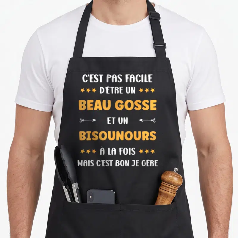 Tablier de cuisine noir avec inscription Beau gosse et Bisounours en typographie orange et blanche.