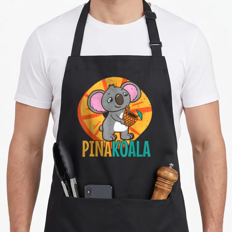 Tablier de cuisine noir avec illustration d'un koala tenant un verre d'ananas et le texte PINAKOALA.