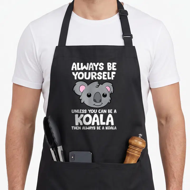 Tablier de cuisine noir avec tête de koala grise oreilles roses et texte blanc Always be yourself unless you can be a koala then always be a koala