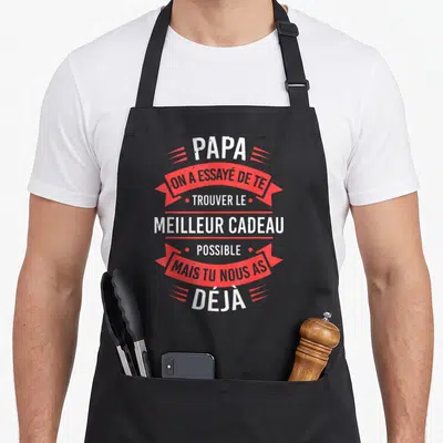 Tablier de cuisine noir avec inscription blanche et bannières rouges disant Papa on a essayé de te trouver le meilleur cadeau possible