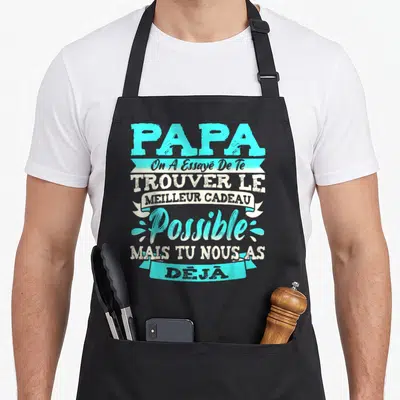 Tablier de cuisine noir avec inscription typographique turquoise et blanche célébrant le papa