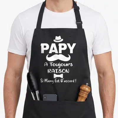 Tablier de cuisine noir avec inscription blanche Papy a toujours raison et un moufette stylisée au centre.