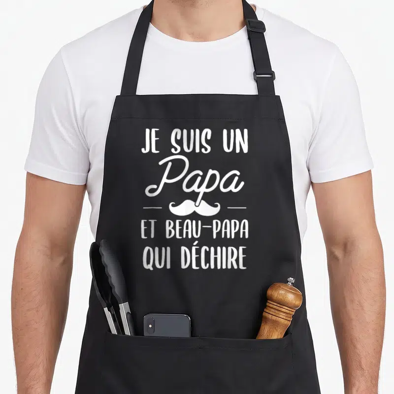 Tablier de cuisine noir avec inscription blanche Je suis un Papa et beau-papa qui déchire surmonté d'une moustache stylisée.