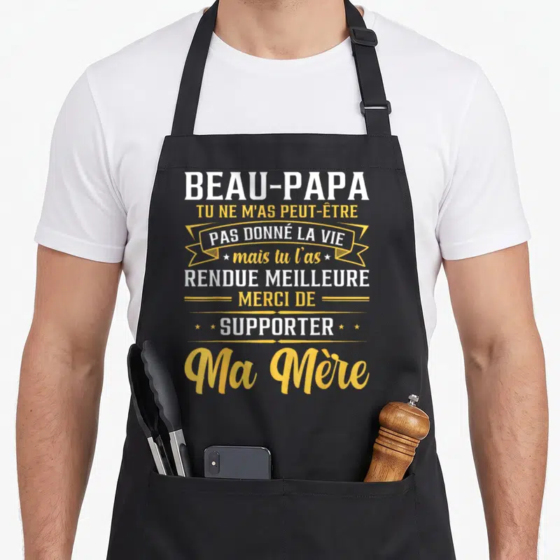 Tablier de cuisine noir avec inscription blanche et jaune rendant hommage au beau-papa pour avoir supporté la mère du porteur.