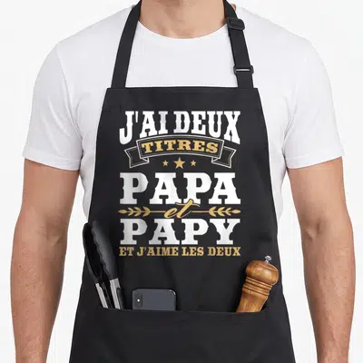 Tablier de cuisine noir avec inscription blanche et dorée J'ai deux titres papa et papy et j'aime les deux.