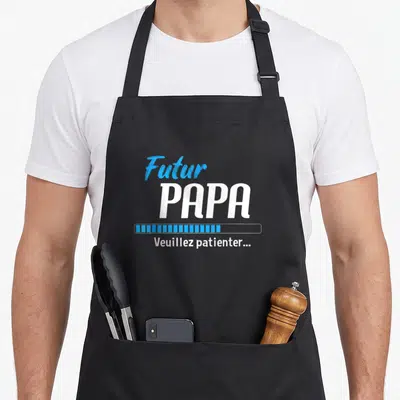 Tablier de cuisine noir avec inscription Futur Papa en blanc et bleu, barre de progression et texte Veuillez patienter...