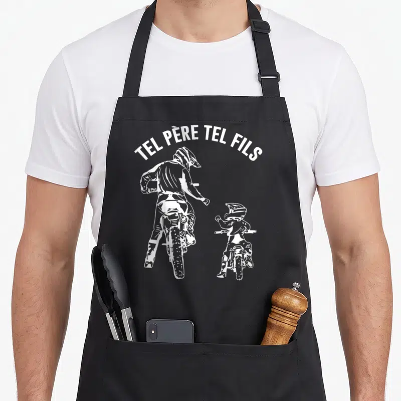 Tablier de cuisine noir avec illustration blanche d'un père et fils en moto cross sous le texte Tel Père Tel Fils.