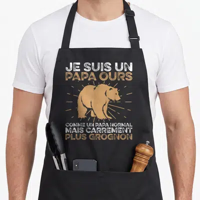 Tablier de cuisine noir avec illustration d'ours orange et texte blanc et ocre sur fond uni.