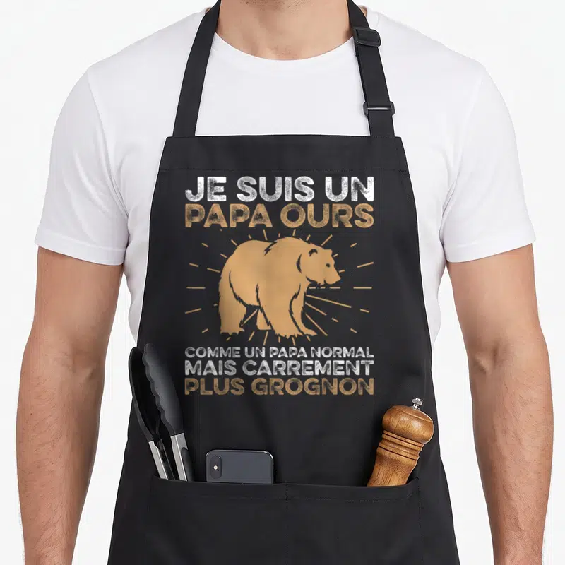 Tablier de cuisine noir avec illustration d'ours orange et texte blanc et ocre sur fond uni.