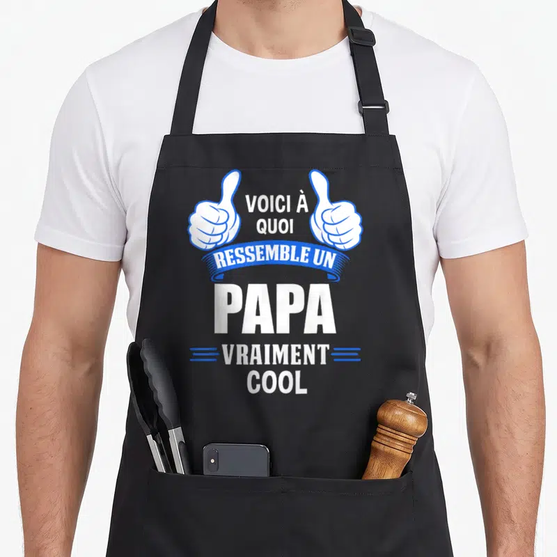 Tablier de cuisine noir avec deux pouces levés et le texte Voici à quoi ressemble un papa vraiment cool en blanc et bleu.