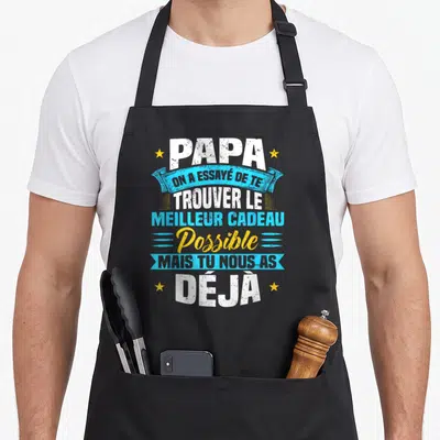 Tablier de cuisine noir avec inscription blanche et bleue on a essayé de te trouver le meilleur cadeau possible déjà entouré d'étoiles jaunes.