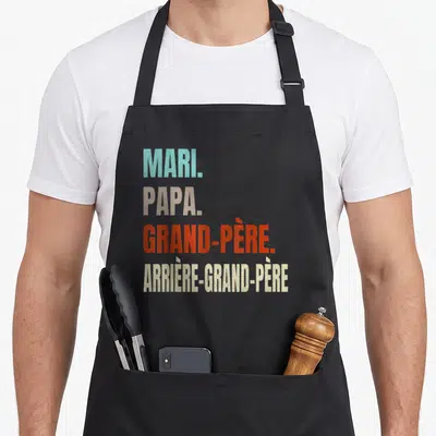 Tablier de cuisine noir avec les mots Mari Papa Grand-Père et Arrière-Grand-Père imprimés en couleurs vives.