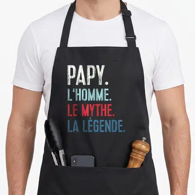 Tablier de cuisine noir avec l'inscription Papy l'homme le mythe la légende en lettres blanches bleues et rouges.