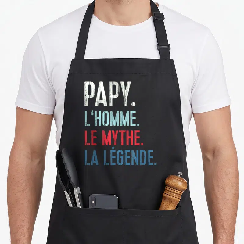 Tablier de cuisine noir avec l'inscription Papy l'homme le mythe la légende en lettres blanches bleues et rouges.