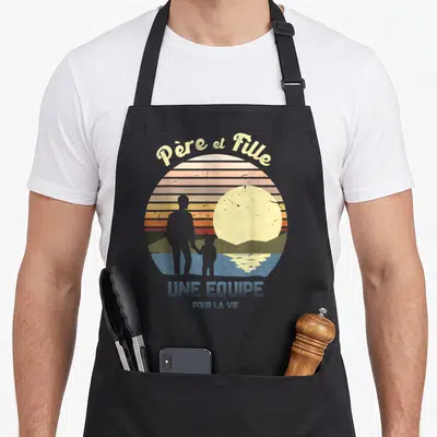 Tablier de cuisine noir avec illustration vintage Père et Fille et une équipe pour la vie sur fond de soleil couchant.