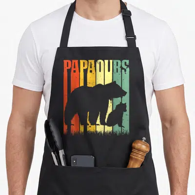 Tablier de cuisine noir avec silhouette d'ours et inscription PAPAOURS multicolore style rétro.