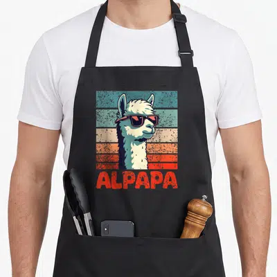 Tablier de cuisine noir avec illustration d'alpaga portant des lunettes de soleil et le texte ALPAPA en rouge.