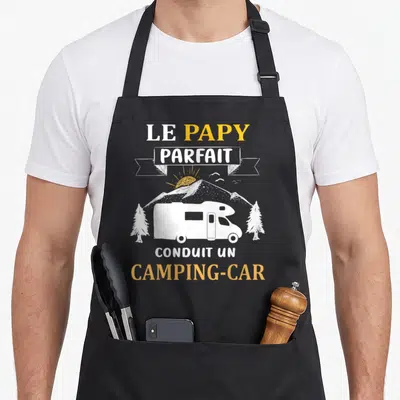 Tablier de cuisine noir avec illustration d'un camping-car blanc, montagnes et texte Le Papy Parfait Conduit Un Camping-Car.