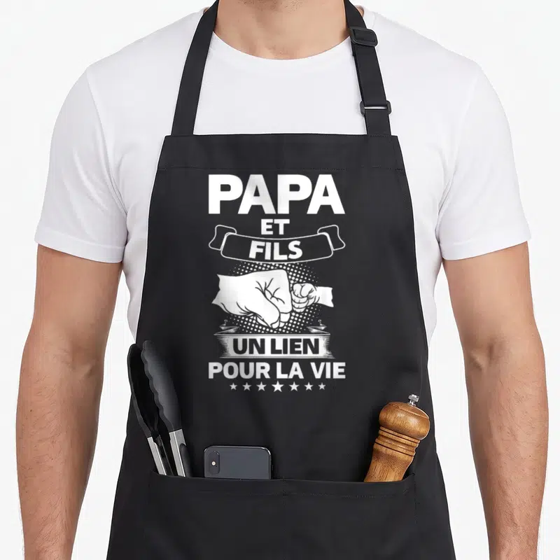 Tablier de cuisine noir avec inscription blanche Papa et Fils Un Lien Pour la Vie et illustration de poings pressés.