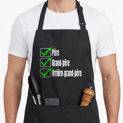 Tablier de cuisine noir avec trois cases à cocher vertes et les mots Père Grand-père Arrière-grand-père en blanc.
