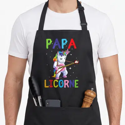 Tablier de cuisine noir avec un licorne blanc jouant de la guitare et le texte Papa Licorne multicolore.