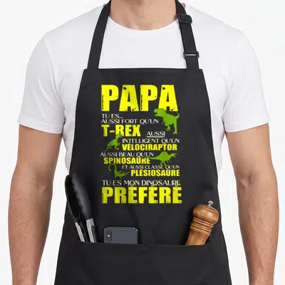 Tablier de cuisine noir avec l inscription Papa T Rex et silhouettes de dinosaures verts et jaunes.