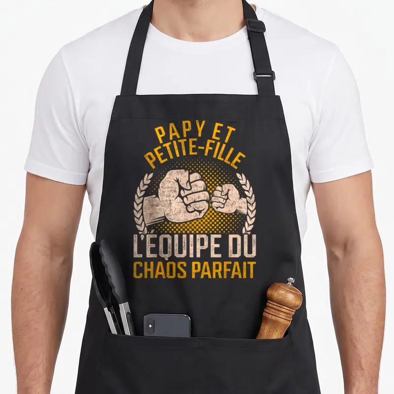 Tablier de cuisine noir avec poings se touchant et texte Papy et petite-fille l'équipe du chaos parfait en orange et beige.
