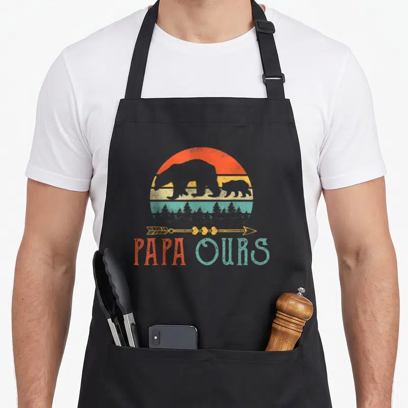 Tablier de cuisine noir avec illustration vintage Papa Ours, silhouettes d'ours et flèche décorative sur fond coloré.