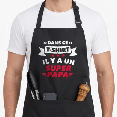 Tablier de cuisine noir avec inscription blanche et rouge « Dans ce super Papa » sur fond uni.