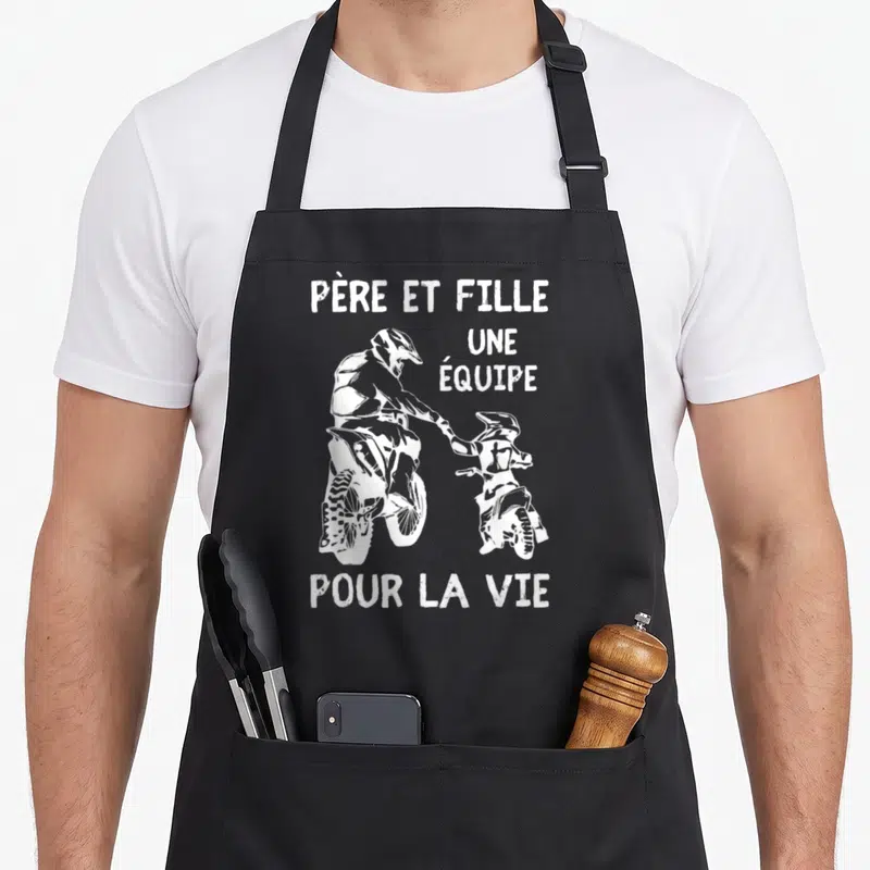 Tablier de cuisine noir avec illustration blanche d'un père et une fille en tenue de motocross se tenant la main.