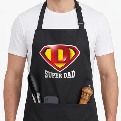 Tablier de cuisine noir avec un écusson rouge jaune portant la lettre D et l'inscription Super Dad en blanc.