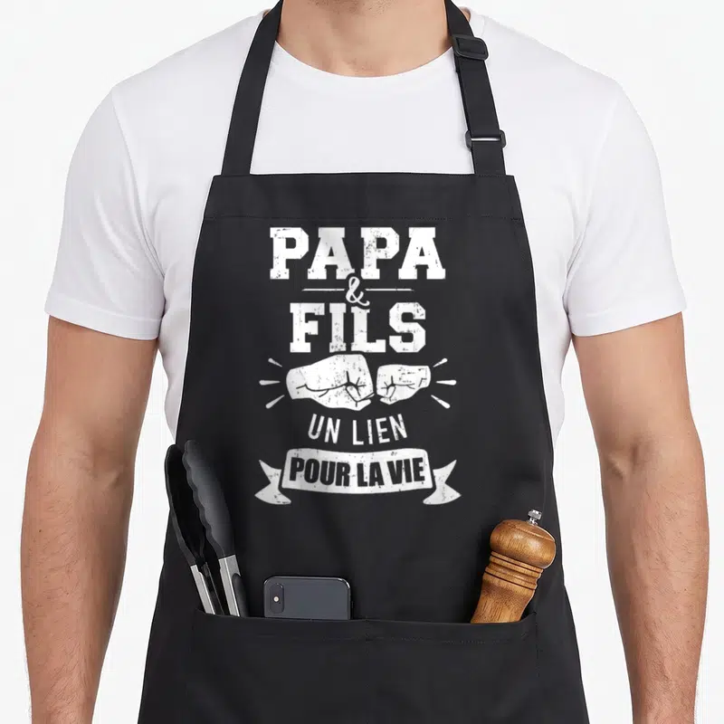 Tablier de cuisine noir avec inscription Papa et Fils un lien pour la vie et illustration de poings.