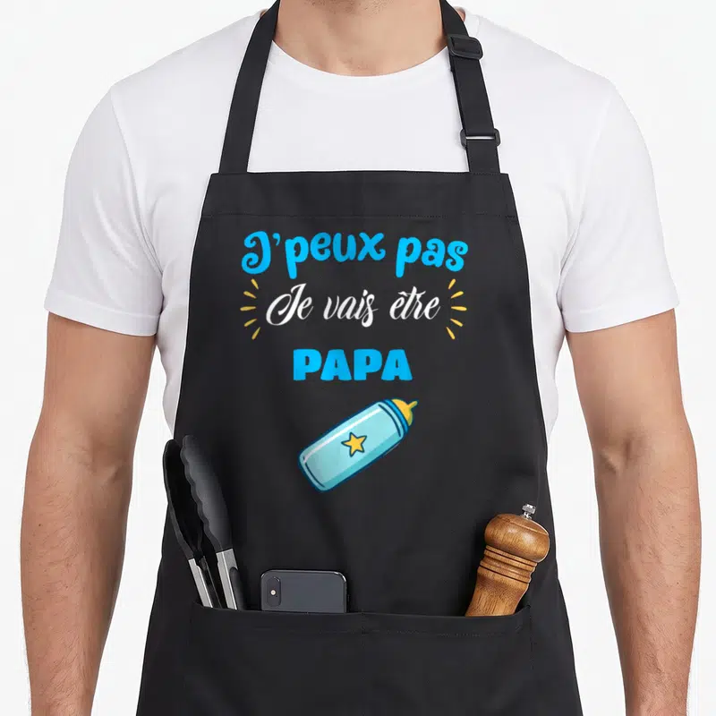 Tablier de cuisine noir avec inscription J'peux pas Je vais être PAPA et illustration de biberon bleu à étoile jaune.
