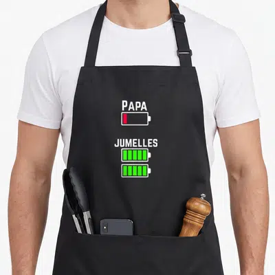 Tablier de cuisine noir avec icônes de batteries Papa et Jumelles imprimées en blanc, rouge et vert.