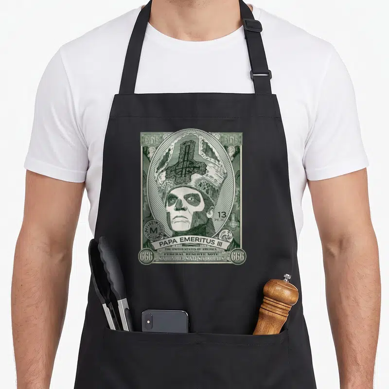 Tablier de cuisine noir avec illustration verte imitant un billet de banque représentant un crâne en tenue épiscopale et le texte Papa Emeritus III.