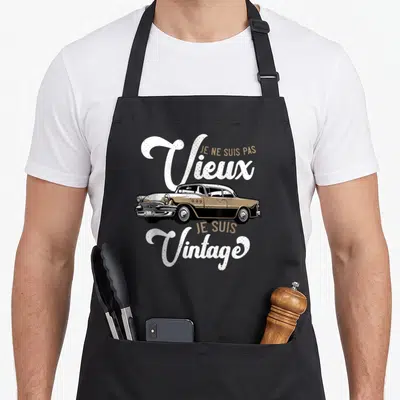 Tablier de cuisine noir avec une voiture vintage beige et les mots Je Ne Suis Pas Vieux Je Suis Vintage en blanc.