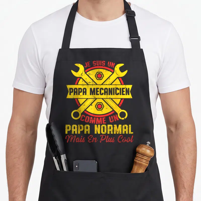 Tablier de cuisine noir avec deux clés jaunes croisées et le texte Je Suis Un Papa Mécanicien en rouge et jaune.