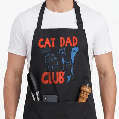 Tablier de cuisine noir avec inscription Cat Dad Club en rouge et illustrations de chats stylisés en bleu vif.