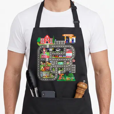 Tablier de cuisine noir avec circuit de course coloré incluant une police, une caserne de pompiers et une école.