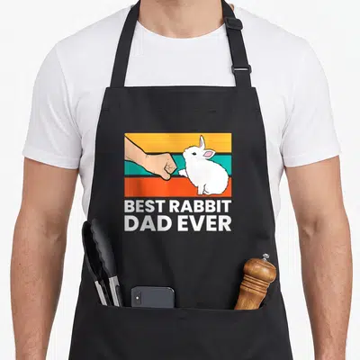 Tablier de cuisine noir avec illustration d'une poignée de main entre une main humaine et un lapin blanc sur bandes colorées.