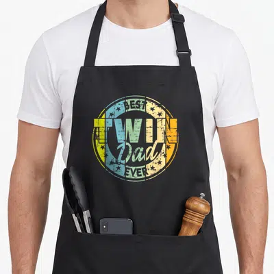Tablier de cuisine noir avec un logo circulaire multicolore affichant Best Twin Dad Ever entouré d'étoiles.