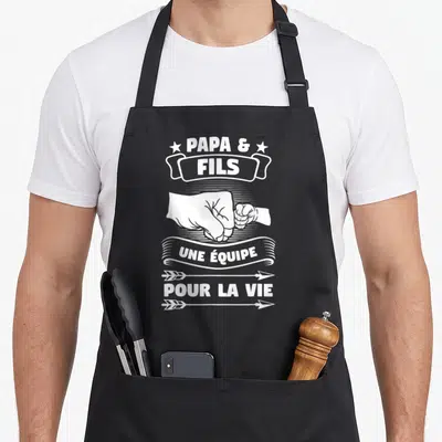 Tablier de cuisine noir avec inscription Papa et Fils une équipe pour la vie et illustration de deux poings se touchant en blanc.